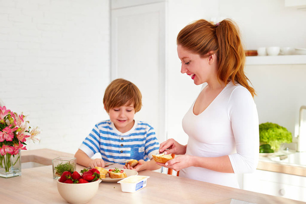 happy mother and son preparing snacks in the morning at home kitchen - Zdjęcie, obraz