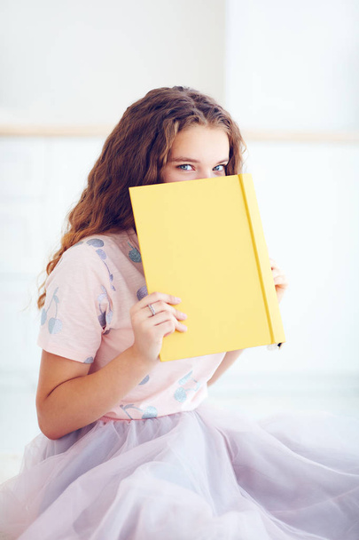 beautiful young girl hiding face behind the book - Фото, изображение