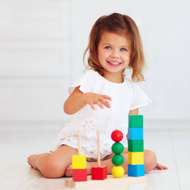 cute little baby girl playing with wooden toy on the floor - Foto, Imagem