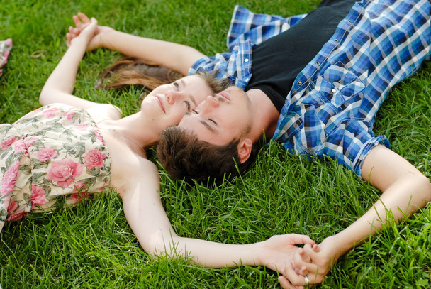 Young happy couple man and woman lying on green lawn - Zdjęcie, obraz