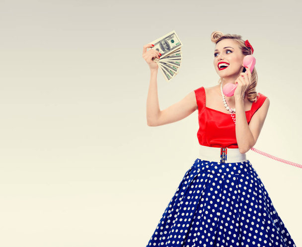 woman with money, talking on phone, dressed in pin-up style dres - Fotó, kép