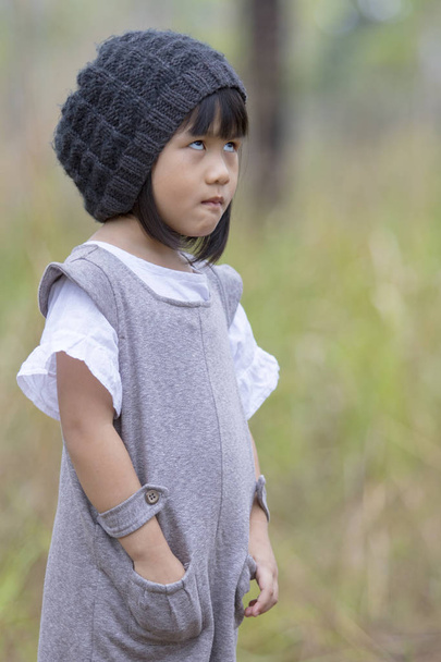 lustiges Gesicht eines asiatischen Mädchens, das auf einem Feld mit grünem unscharfen Backg steht - Foto, Bild