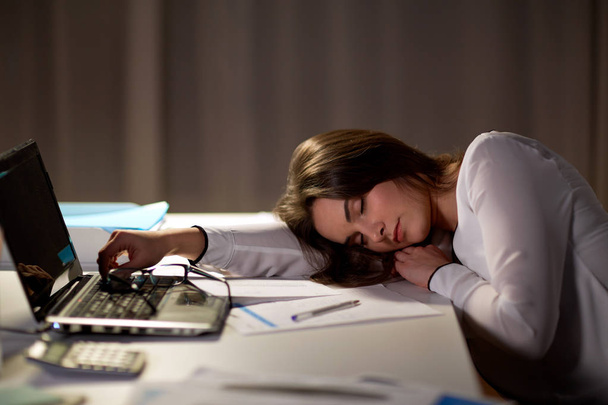 mujer cansada durmiendo en la mesa de la oficina por la noche
 - Foto, Imagen
