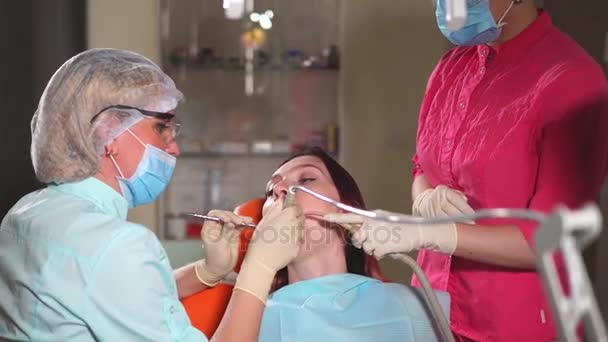 Lekarz ortodonta traktuje pacjenta gabinet dentystyczny, który przyszedł do pielęgnacji jamy ustnej - Materiał filmowy, wideo