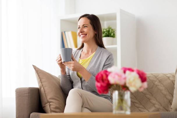Gelukkige vrouw, drinken van thee of koffie thuis - Foto, afbeelding