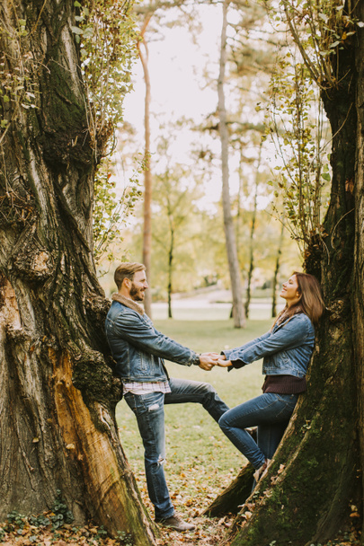 улыбающаяся пара обнимается в осеннем парке - Фото, изображение