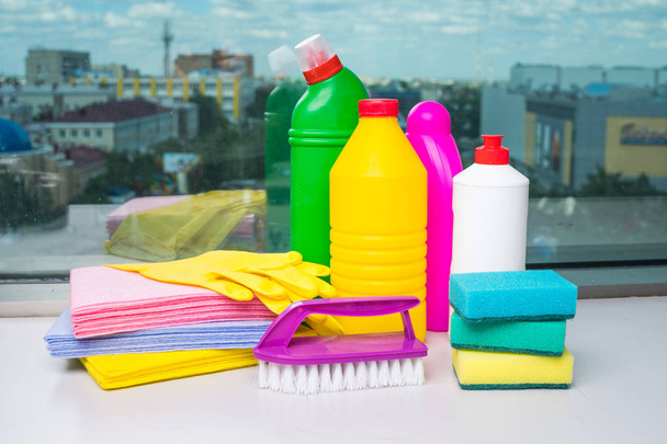 Takarítás a hazai termékek választéka. Mosó-és tisztítószerek, kémiai palackok, takarítás a szivacsok és a kesztyűt. A háttérben az ablak. - Fotó, kép