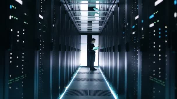 Ingegnere IT maschile Lavora su un computer portatile in un Big Data Center. Righe di server rack sono visti
. - Filmati, video