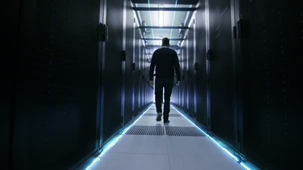 Après coup de l'ingénieur informatique marchant dans le couloir du centre de données avec des rangées de serveurs de rack
. - Séquence, vidéo