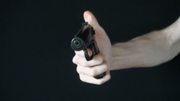 młody człowiek kieruje na aparat z pistoletu czarny i próbuje strzelić - Materiał filmowy, wideo