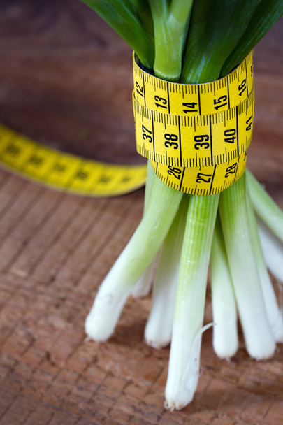 Onion stems and measurement tape - Foto, afbeelding