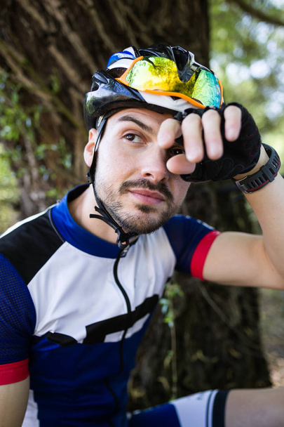Handsome young man relaxing after cycling in the mountain. - 写真・画像