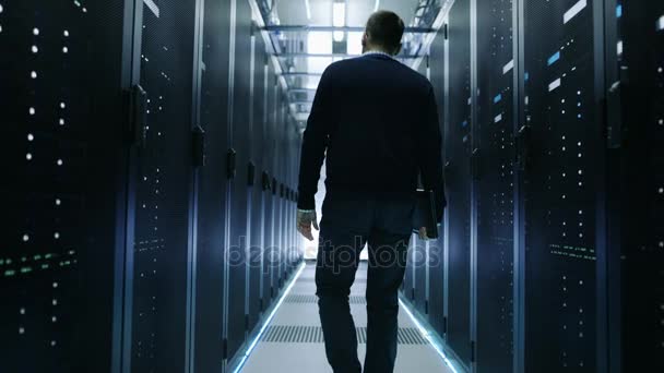 Back View of IT Engineer Walking Through Data Center with Working Rack Servers.  - Footage, Video
