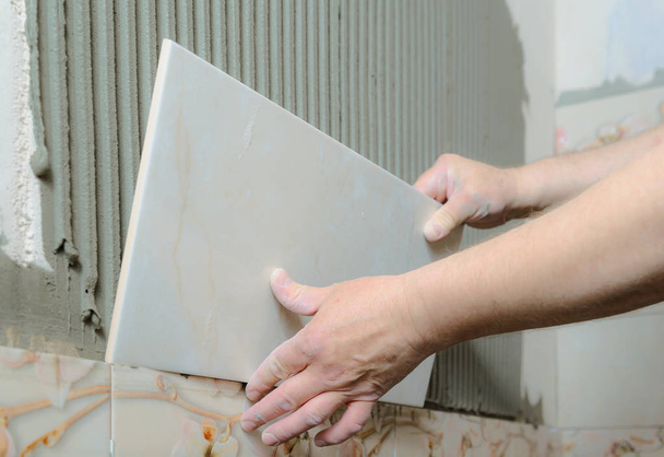 Tilers hands are  installing a ceramic tile. - Photo, Image