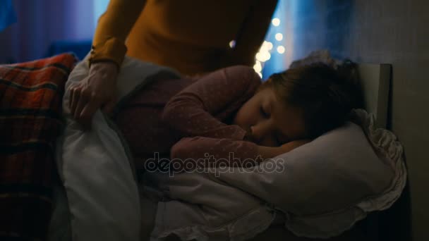 Tatlı küçük kız yatağında geceleri, onun annesi Tucks onu battaniyeye uyur. - Video, Çekim