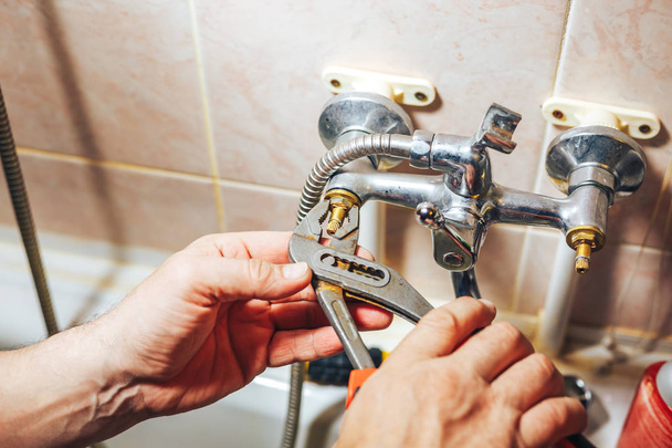 Man repair and fixing leaky old faucet in bathroom - Фото, изображение