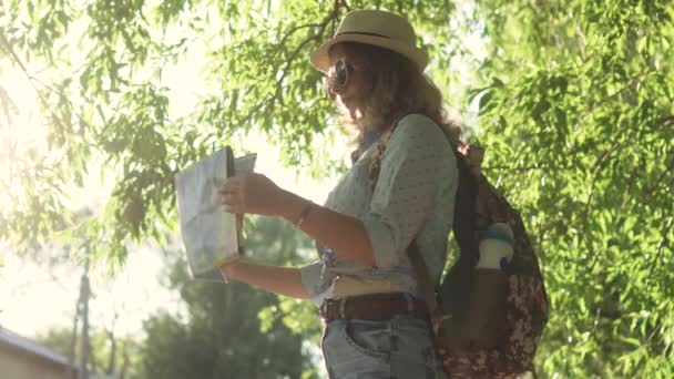 tyttö on turisti valitsee matkakohde kartalla. nuori nainen hipster aurinkolasit ja hattu
 - Materiaali, video