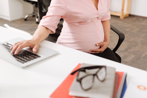 Professional pregnant office worker sitting in at the table - Photo, image