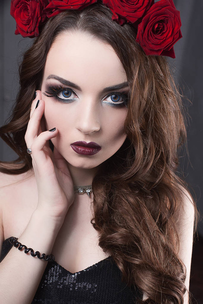 mooie jonge vrouw met rozen bloem in de haren. schoonheid meisje met make-up op donkere achtergrond. donker rood lips.close-up mode geretoucheerd portret - Foto, afbeelding