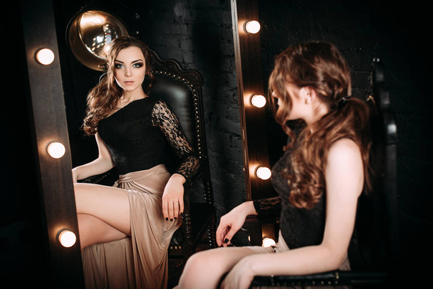 Yksilöllisyys. Ajattelevainen tyylikäs nainen Black Prom Dress seisoo lähellä peili tummalla taustalla. muoti korjailtu laukaus
 - Valokuva, kuva