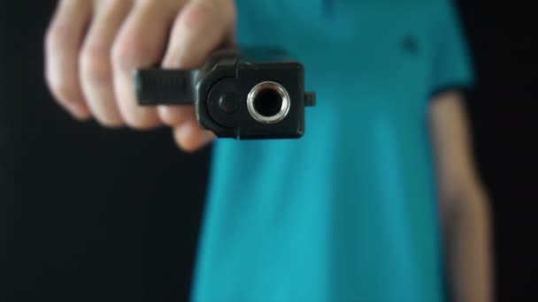 młody człowiek wysyła czarny pistolet na kamery - Materiał filmowy, wideo