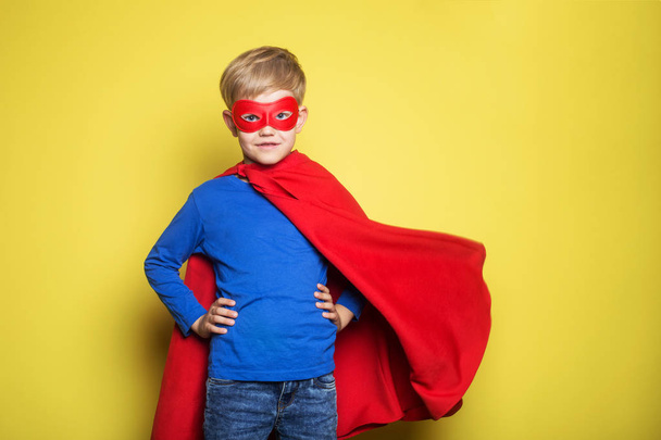 Niño con capa de superhéroe rojo y máscara. Superman. Estudio retrato sobre fondo amarillo
 - Foto, imagen