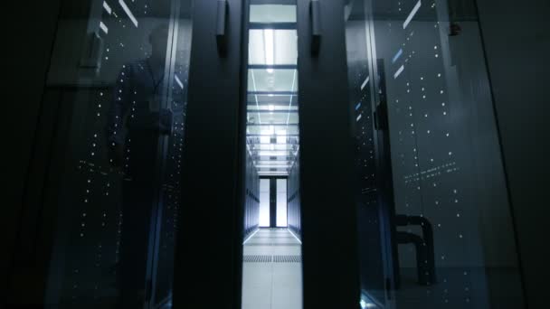 Server Engineer Walks into Opening Sliding Doors and Goes Through Data Center Corridor. Working Server Racks Blink with LED Lights. - Séquence, vidéo