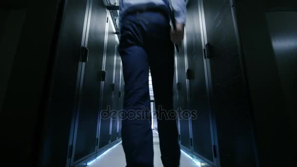 Following Shot of Server Engineer Walking into Opening Sliding Doors and Goes Through Data Center Corridor. Working Server Racks Blink with LED Lights. - Πλάνα, βίντεο