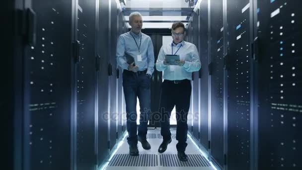 Twee Server technicus werken in datacenter. Gebruik van een Tablet PC. Ze lopen door rijen van Server Racks. - Video