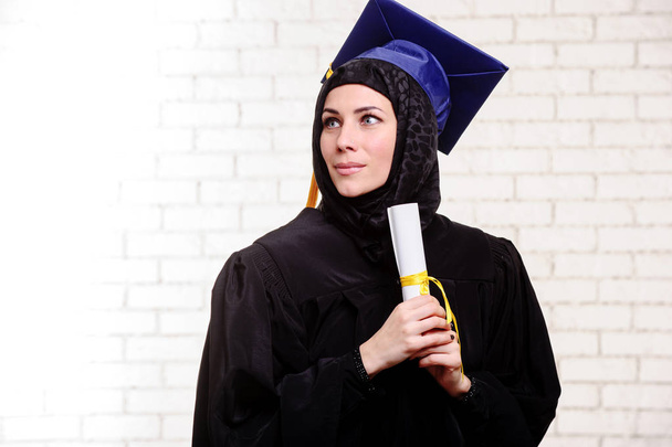 Счастливого выпускника мусульманского студента с дипломом в помещении
. - Фото, изображение
