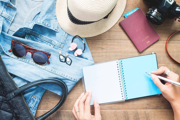 Posa piatta creativa di donna mani pianificazione vacanza viaggio con accessori su spazio di lavoro in legno
 - Foto, immagini