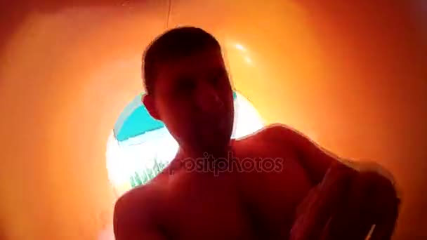 A man inside a pipe in a water park. Aquapark, active recreation, water slides, action camera. - Footage, Video