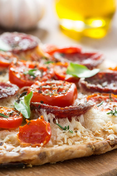 Stück Pizza mit Salami und Tomaten auf einem Holzbrett - Foto, Bild