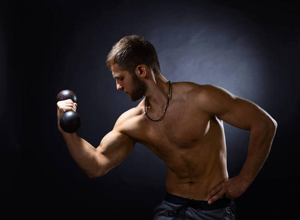 Young bodybuilder on a black background  - Фото, зображення