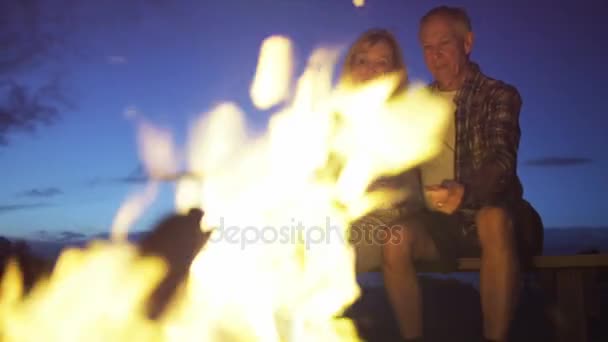 Senioři sedí plameny nad táborák - Záběry, video