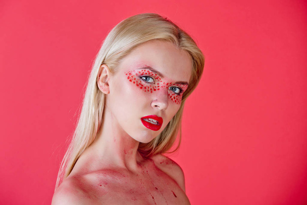 pretty blonde woman with creative fashionable makeup on red background - Valokuva, kuva
