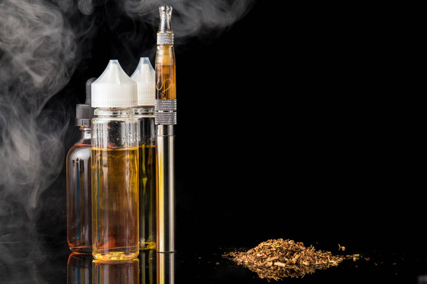 Electronic cigarette with bottles and grinded tobacco leaves - Photo, Image