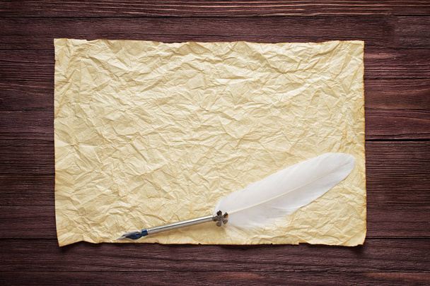 Παλιό χαρτί σε καφέ ξύλο υφή με λευκό φτερό - Φωτογραφία, εικόνα
