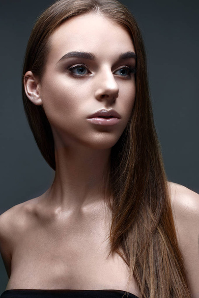 A young girl with straight flowing hair. A beautiful model with a gentle nude makeup and shining skin. - Foto, Imagem