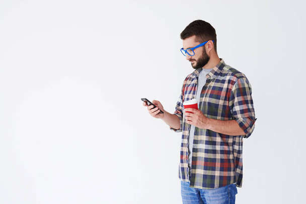 Cheerful bearded man standing with cup of coffee and smartphone  - 写真・画像
