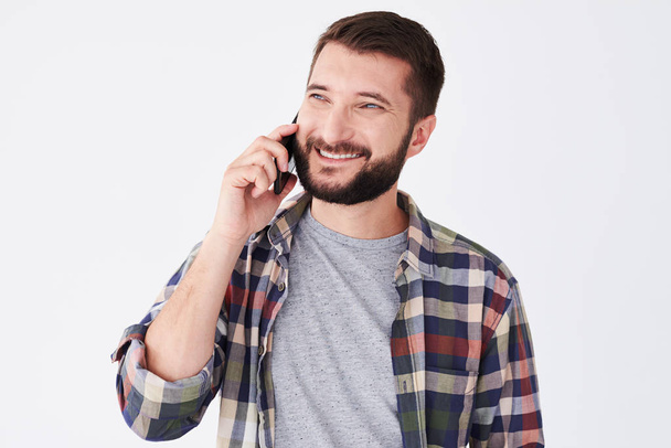 Smiley γενειοφόρος άνδρας μιλάει στο τηλέφωνο ενώ στέκεται - Φωτογραφία, εικόνα