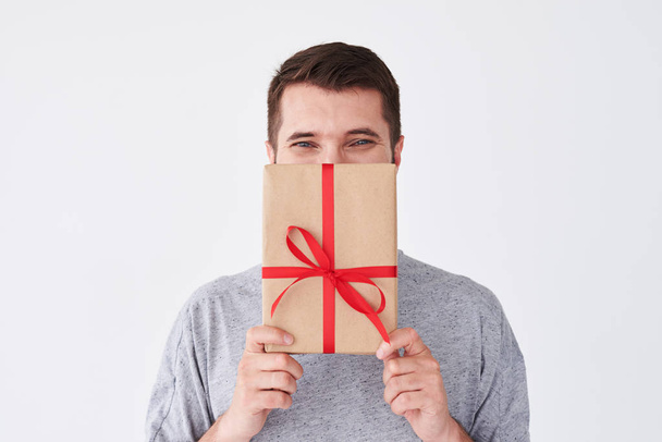 bärtiger Mann, der sein Gesicht mit einem Geschenk bedeckt - Foto, Bild