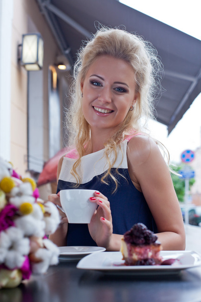 a beautiful young blond girl in summer dress at the table in pav - Fotó, kép