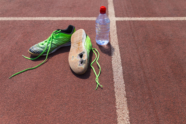Broken green running shoes with water bottle - Photo, Image