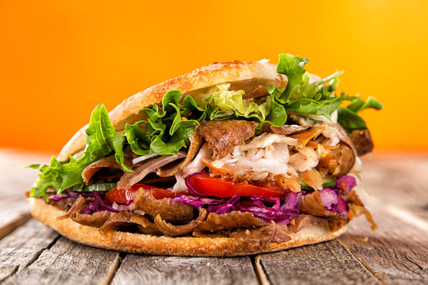 Close up of kebab sandwich on old wooden table. - Photo, image