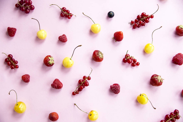 Summer berries are scattered on a pink background - currants, cherries, raspberries and strawberries - Photo, Image