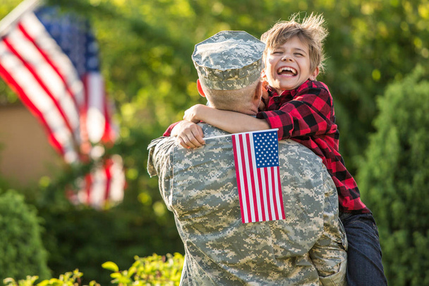 Happy reunion of soldier with family, son hug father with american flag - Photo, Image