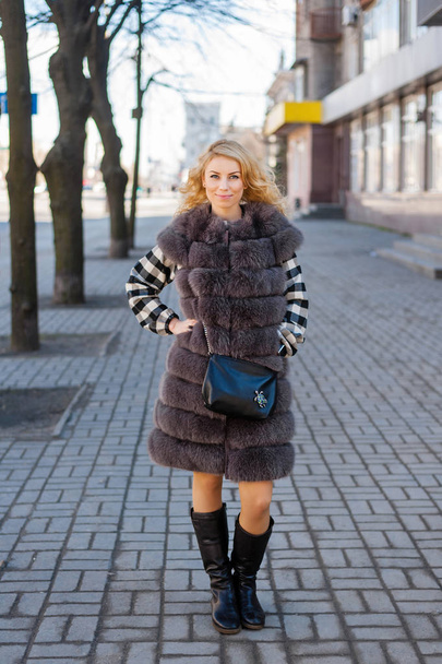 Young girl in a fur coat posing in the city - Zdjęcie, obraz