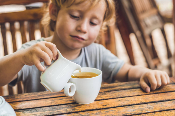  boy pours honey into the tea - Fotoğraf, Görsel