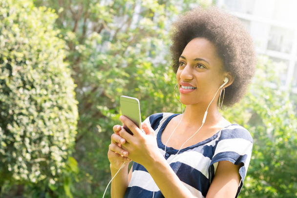 Молода афро-жінка слухає музику з мобільного телефону в парі
 - Фото, зображення